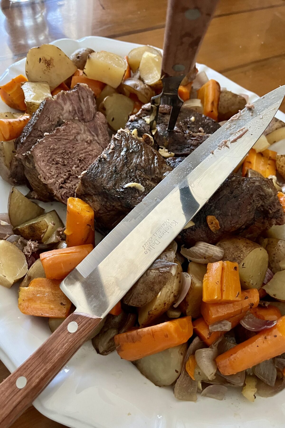 Couple pieces have been cut off of the roast. Fork is stuck in to the roast and there is a nice sitting on top of the roast