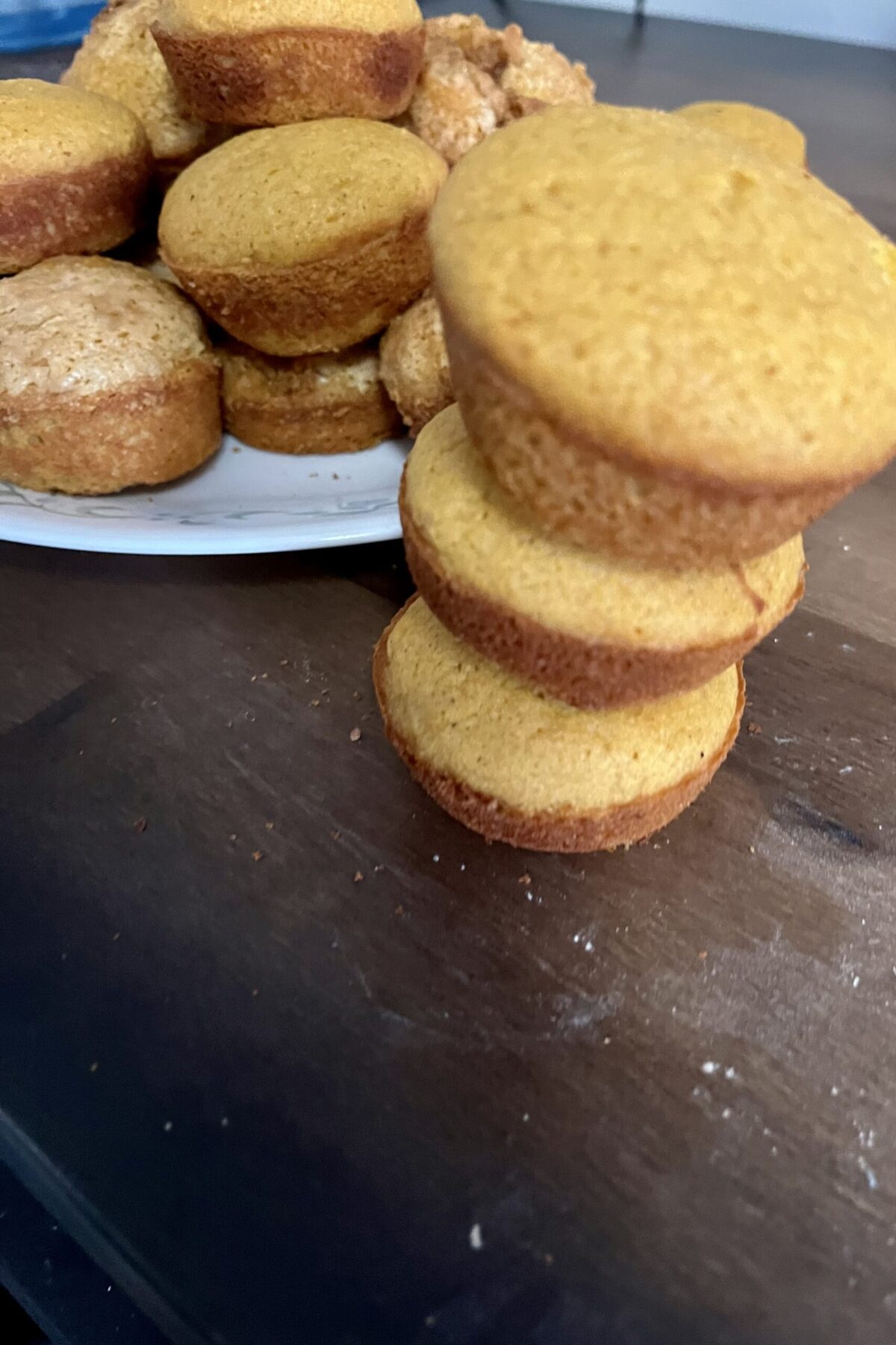 Good nice little tower of muffins with another plate muffins behind it. They have a nice brown top and a darker brown thing you can see that they have nice sugar
