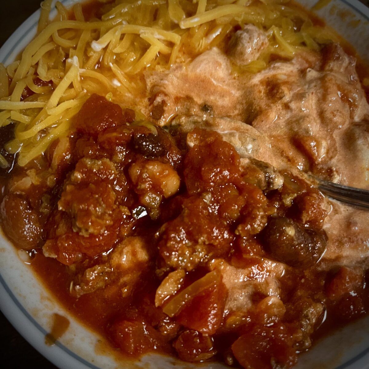 sour cream has been mixed in and a portion of the crockpot turned kind of a lighter pink color in some areas and then you have the cheese that’s melting into the chili still has a relatively dark color