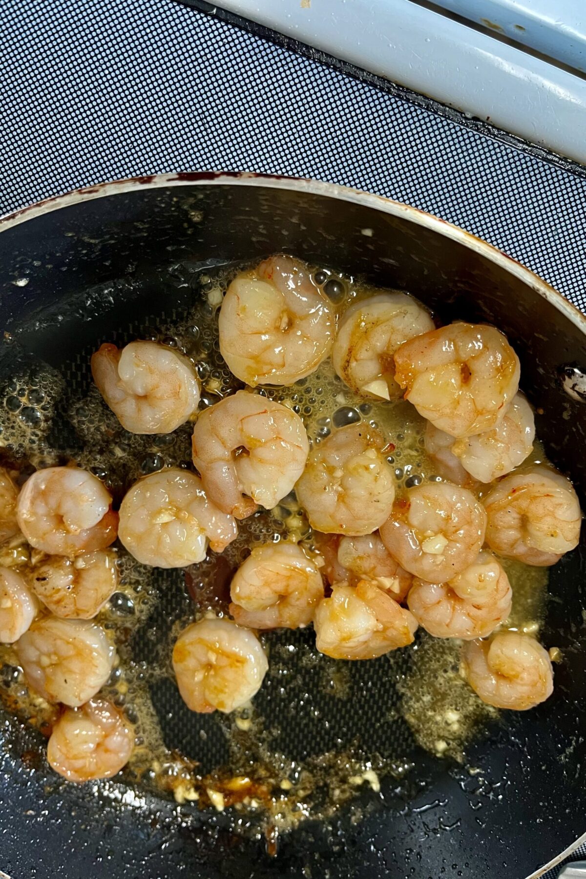 The mail and chili sauce have been added in with the shrimp. I’ve been coating a little bit onto them so that sticks better help dry it out a little bit as well. if you’re gonna have more of a golden color to them now is bubbling slightly from the heat of the pan and sticky