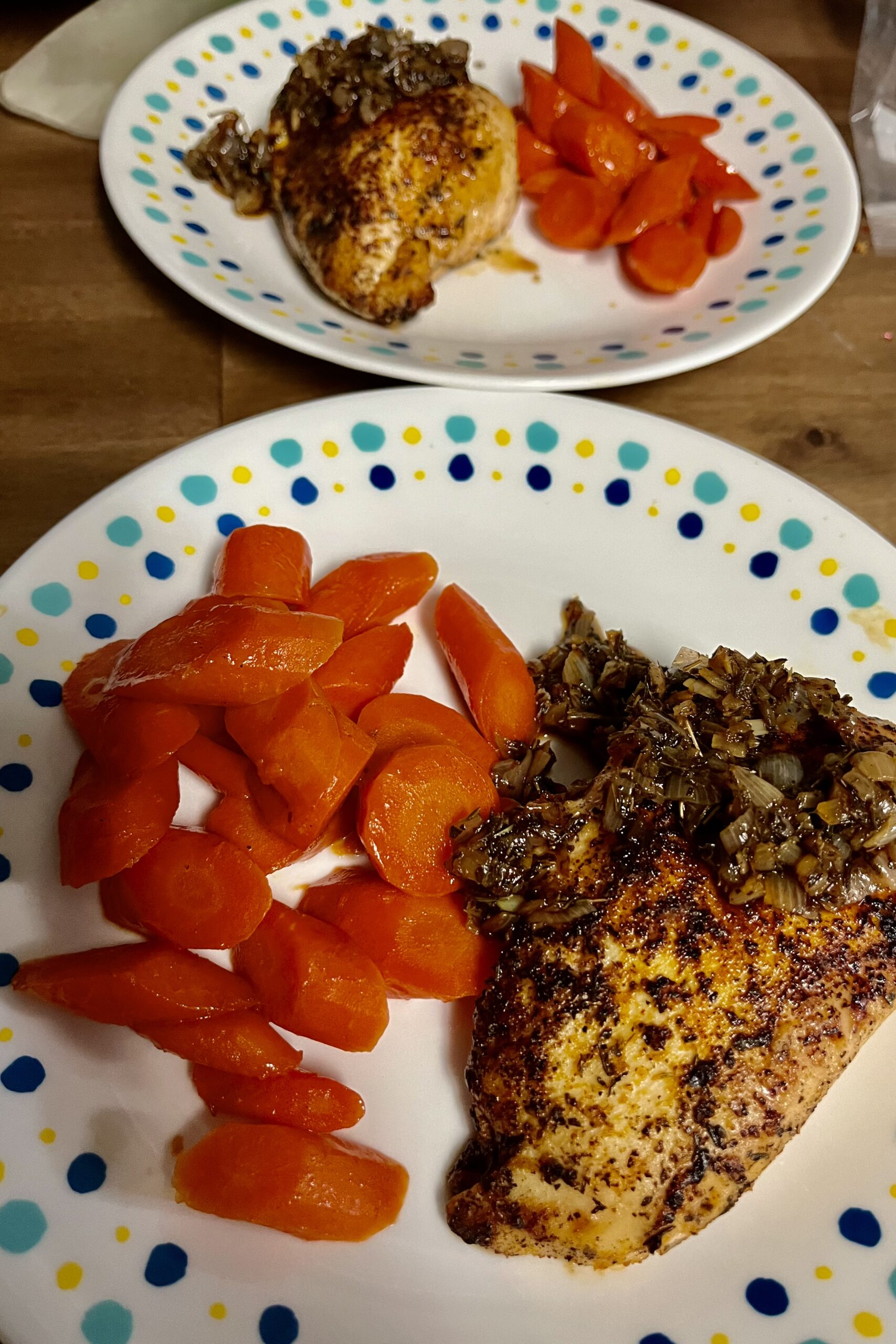 Two plates is chicken Demi glaze with glazed carrots. They switch over from each other carrot a on side and chicken on the other