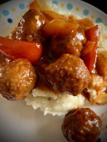 Image of the hot pot BBQ meatballs, meatballs have been added on top of some mashed Five meatballs on the side also see some peppers on mashed potatoes as well