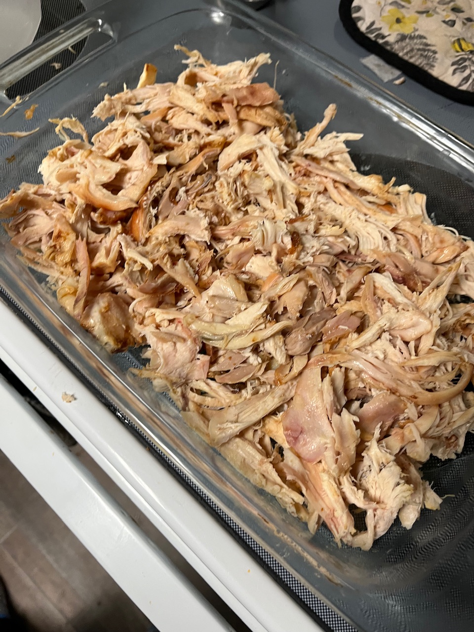 Rotisserie chicken has been pulled apart and placed in the bed out of the baking dish and also see a little bit of the butter on the sides from where the butter is melted