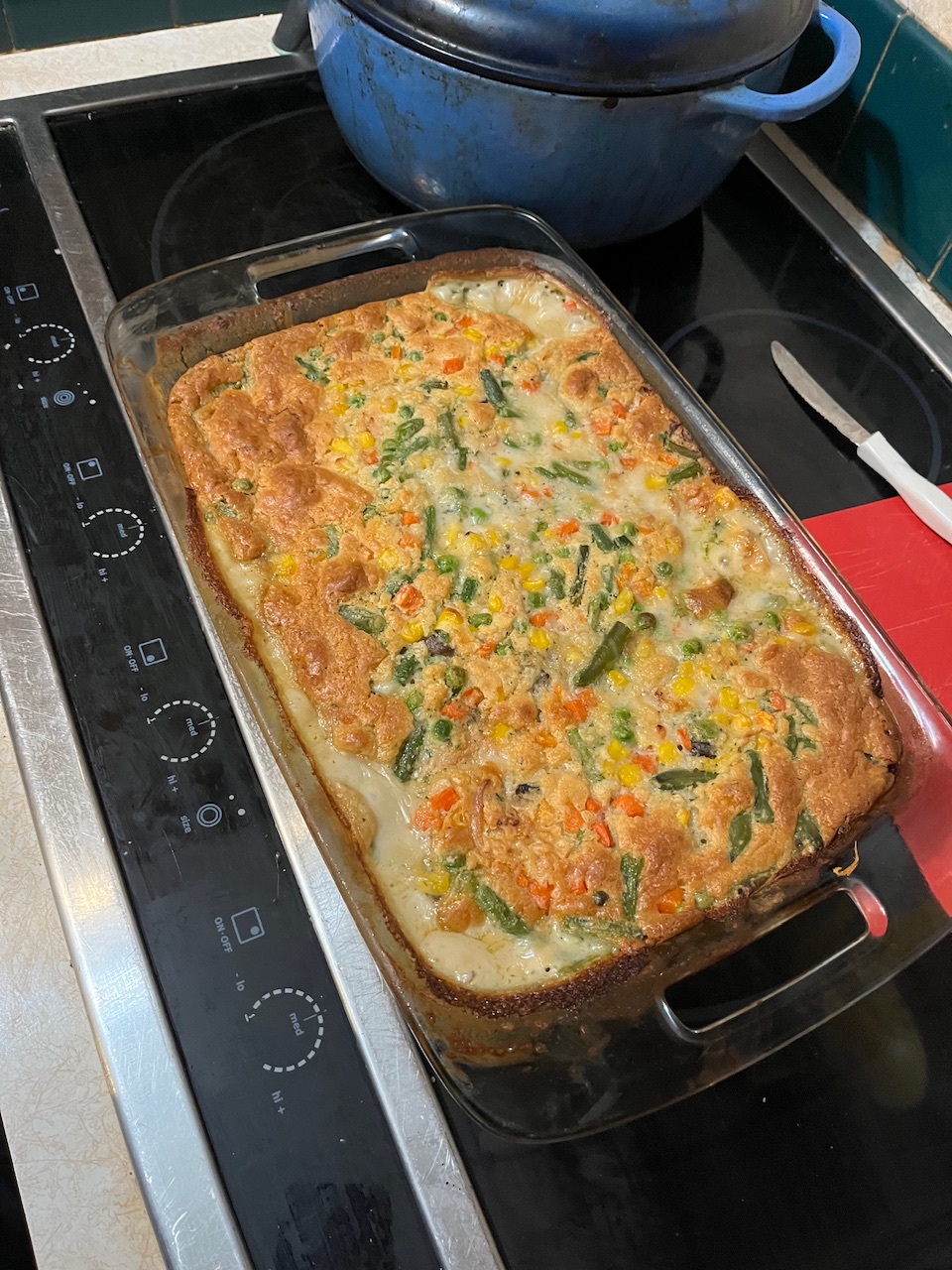 Shows the chicken cobbler completed. You can see a bit of carrot, chicken, green beans and corn sticking out. You can also see nice golden cross and part of it over all of it.