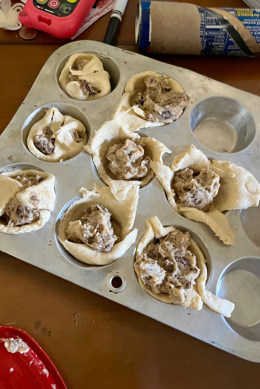 Coresent rolls have been placed in muffin tin and sausage gravy has been added to them