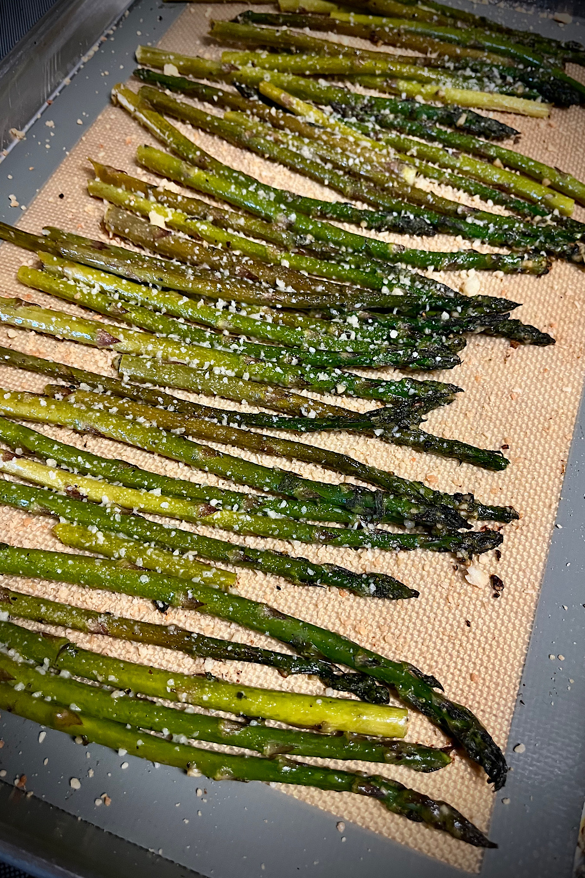 Asparagus is laid out all in one layer. See you later Parmesan cheese that has been sprinkled up on them.