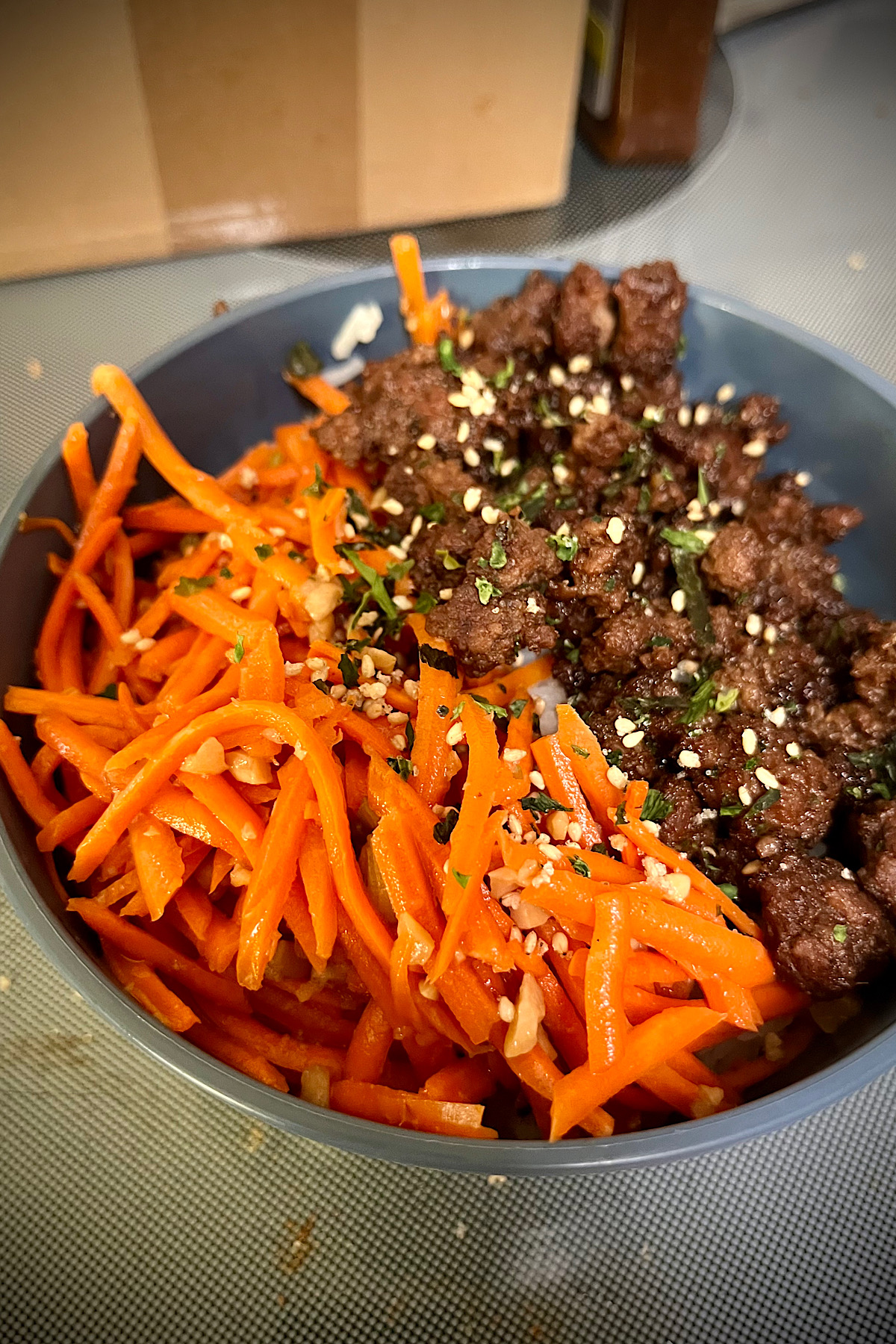 Characters are sitting in the front of the ball, threaded giving a nice light contrast to the dark beef all sitting in a gray bowl with a little flex so sesame seeds flavoring, and seaweed