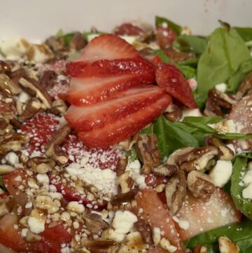 Easy strawberry spinach salad with feta cheese, pecans, and balsamic dressing served in a large bowl.